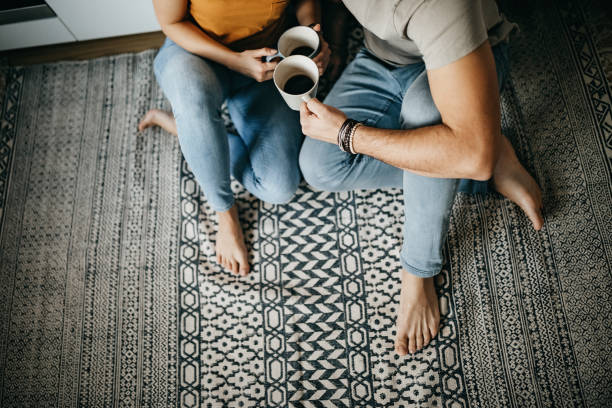 Couple drinking coffee sitting on area rug | IQ Floors